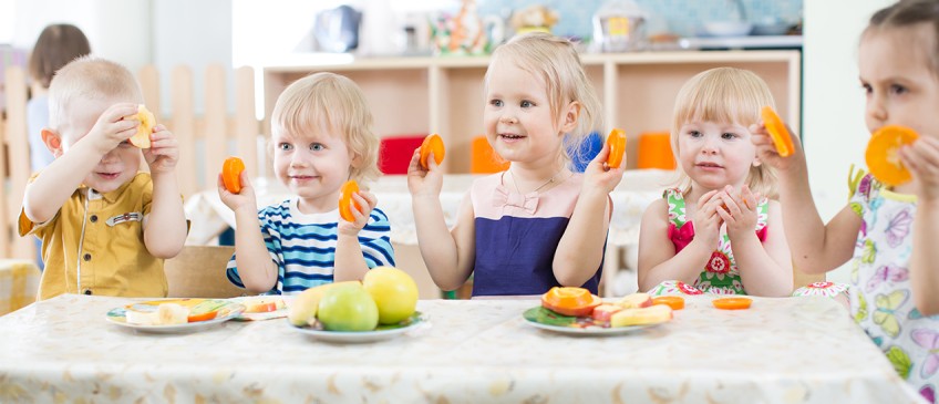 Ratgeber Kita-Anspruch - Kindergartenkinder halten Obstscheiben hoch